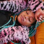 Serene portrait of a woman resting comfortably in colorful, textured clothing.